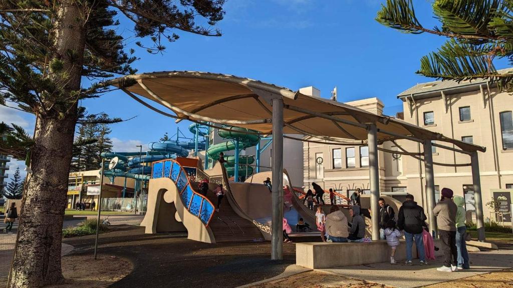 a group of people standing under a play structure at Glenelg resort style beachside apartment in Glenelg