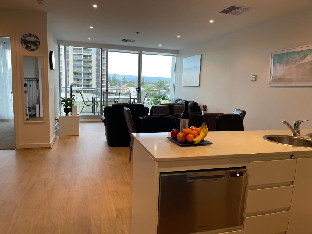 uma cozinha e sala de estar com um sofá e uma mesa em Glenelg resort style beachside apartment em Glenelg