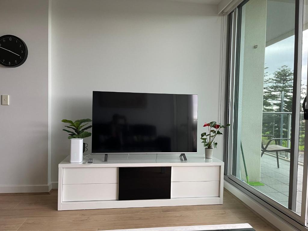 a flat screen tv on a white entertainment center in a living room at Glenelg resort style beachside apartment in Glenelg