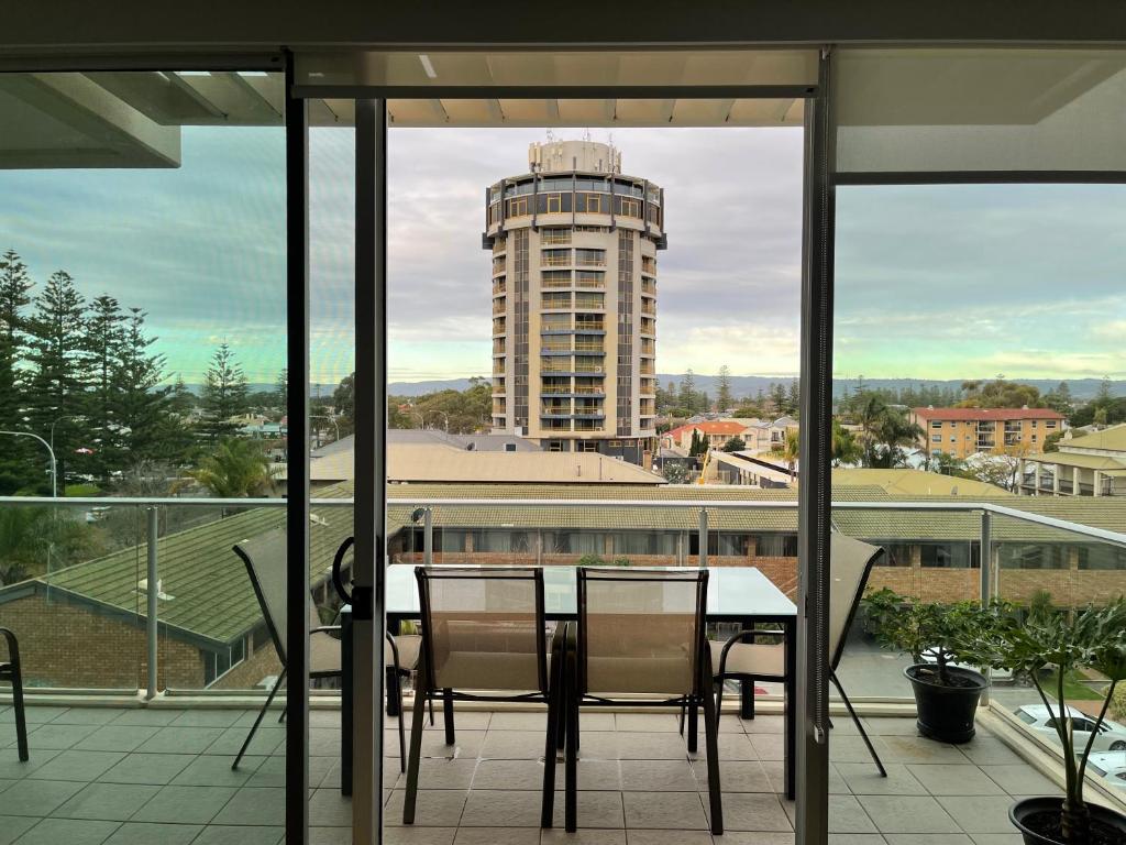 a table and chairs on a balcony with a building at Glenelg resort style beachside apartment in Glenelg