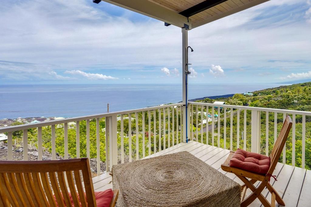 a balcony with a table and chairs and the ocean at Captain Cook Bungalow with Panoramic Ocean Views! in Papa Bay Estates
