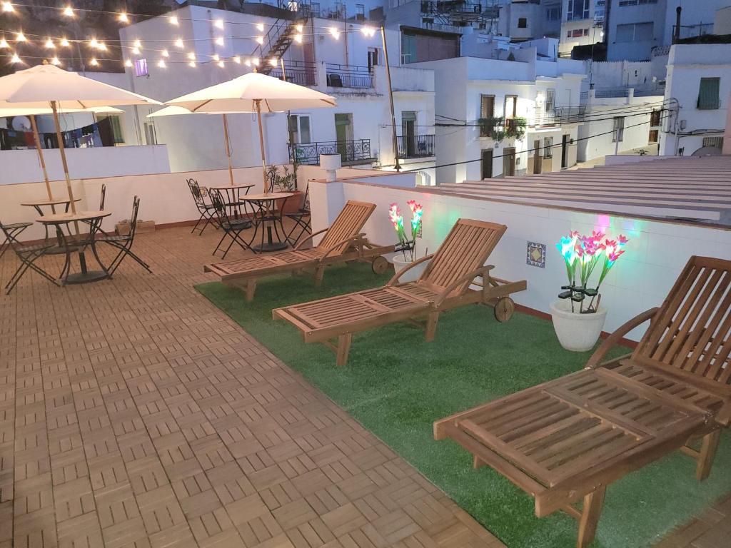 patio z krzesłami, stołami i parasolami w budynku w obiekcie Hostal Jayma w mieście Salobreña