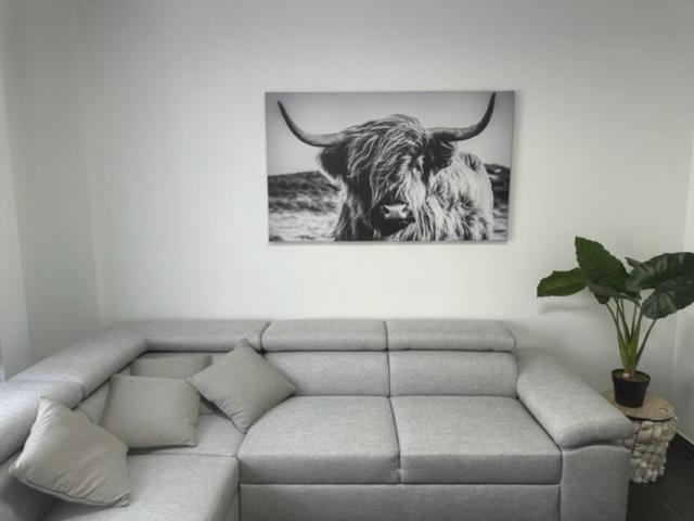 a couch in a living room with a picture of a bull at Appartement Justine in Blankenberge