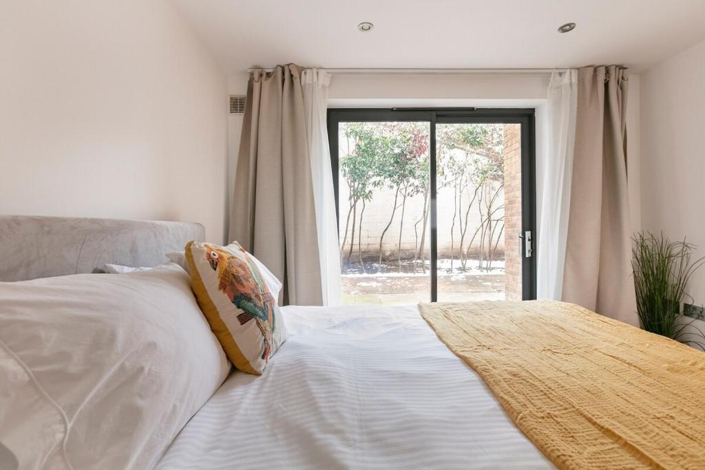 a bedroom with a bed and a large window at Hermitage Road Apartment By Morethanstays in London