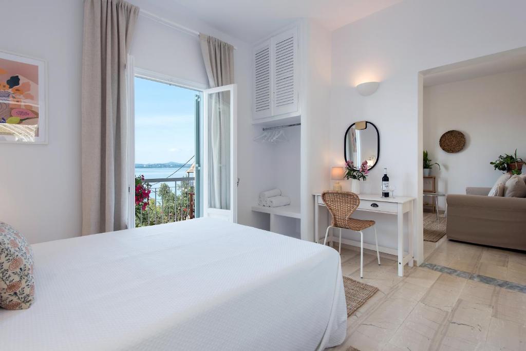 a white bedroom with a bed and a desk and a window at Reana Elegant Apartments in Barbati
