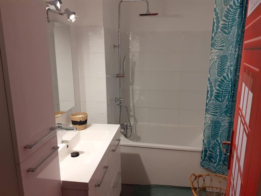 y baño con lavabo blanco y ducha. en Appart Aventure, logement entier + escape game !, en Reims