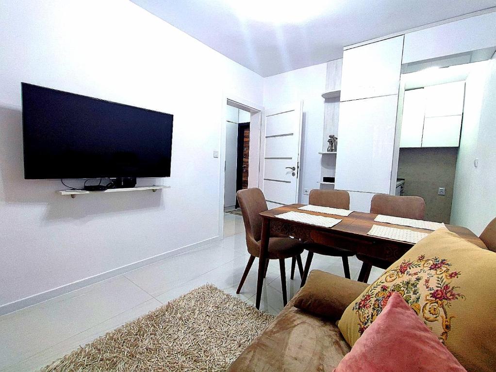 a living room with a table and a tv on a wall at Апартамент Мелани in Varna City