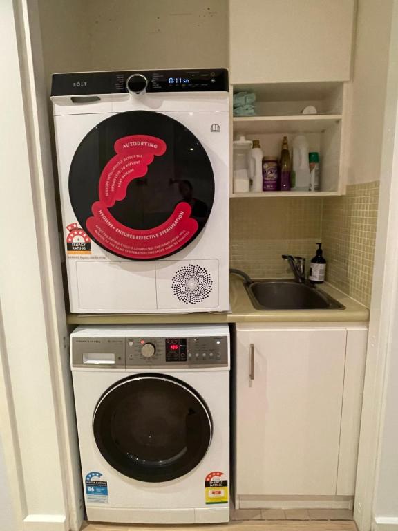 a kitchen with a washing machine and a sink at Glenelg resort style beachside apartment in Glenelg