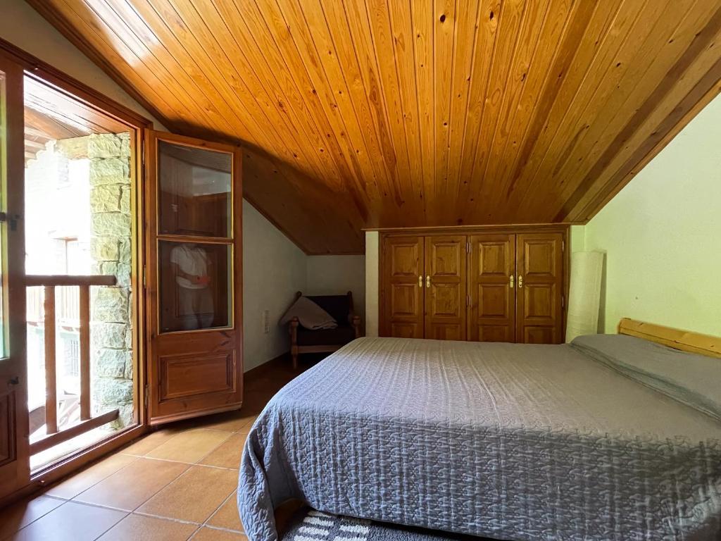 Casa Can Rufo de Rupit في روبيت: غرفة نوم بسرير وسقف خشبي