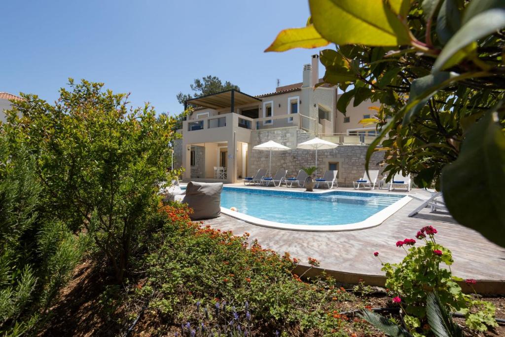 a large house with a swimming pool in front of it at Palladio Luxury Villa in Roussospítion