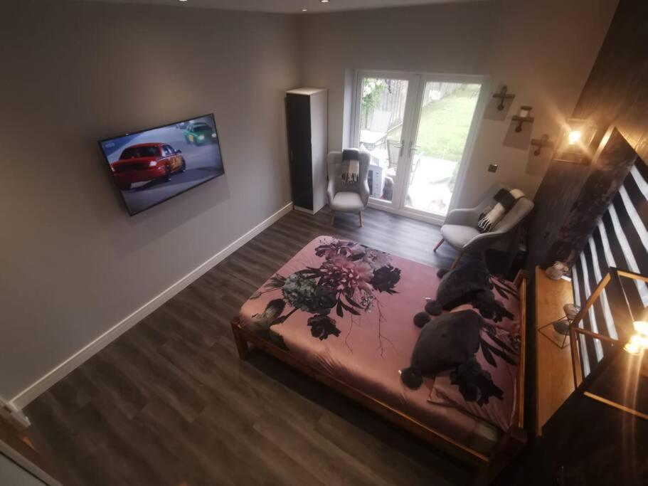 um quarto com uma cama e uma televisão na parede em Beautiful MASONS HIDEAWAY studio apartment em Bridgend