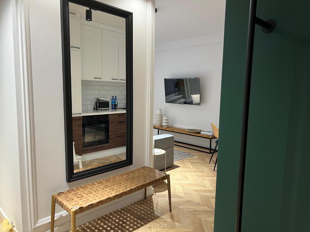 a mirror on a wall with a bench in a room at Apartament Elle in Malbork