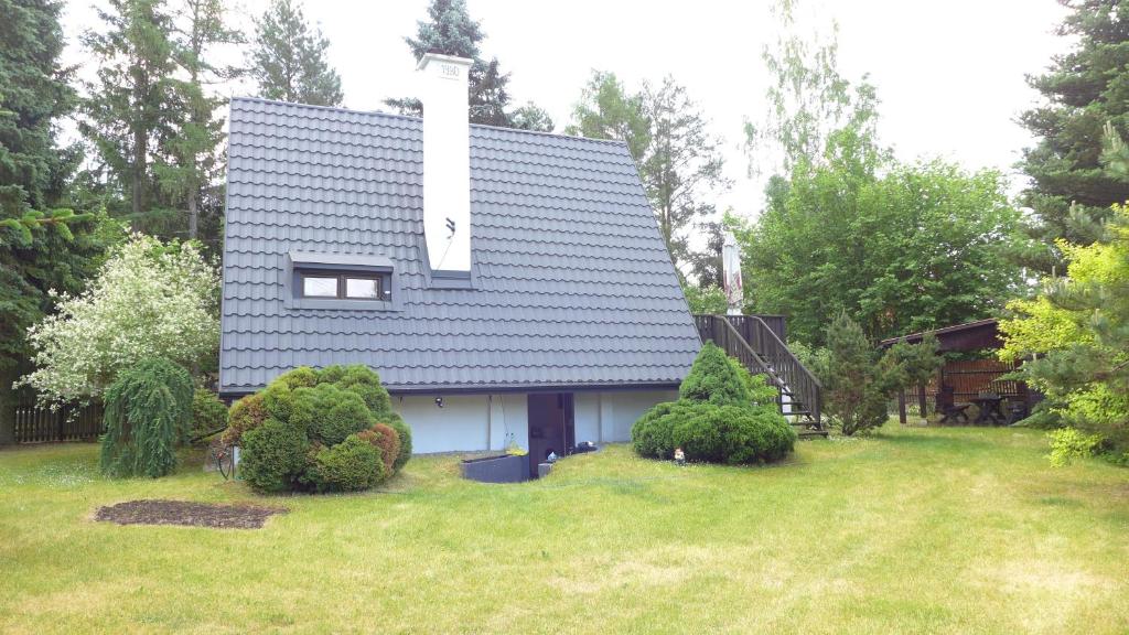uma casa com um telhado azul num quintal em Dom Letniskowy nad Krutynią em Spychowo