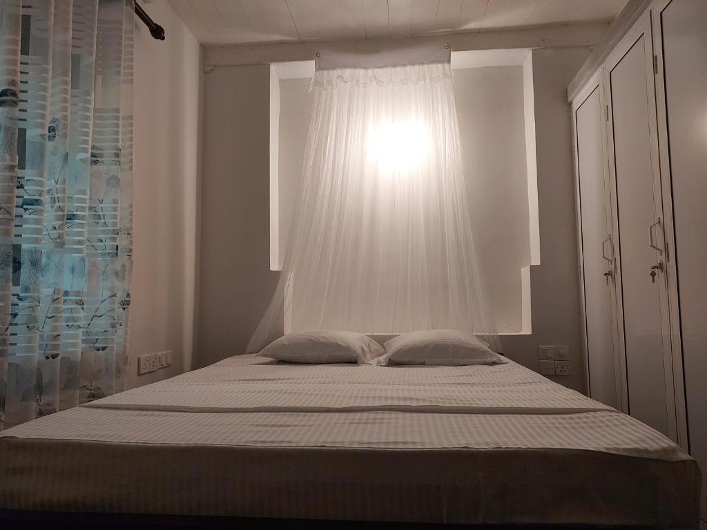 a bed with two pillows in a bedroom with a window at Green Stay in Habaraduwa Central