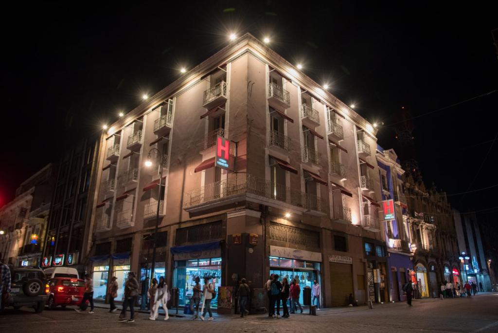 Un bâtiment avec des personnes debout à l'extérieur le soir dans l'établissement Hotel Posada Guadalupe, à Puebla