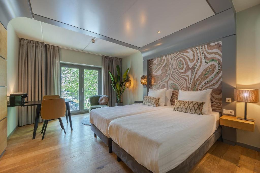 sypialnia z dużym łóżkiem i biurkiem w obiekcie Leonardo Hotel Breda City Center w mieście Breda