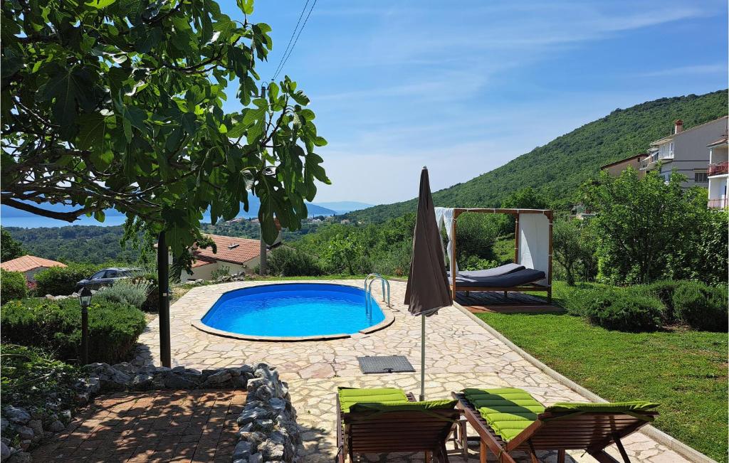 a swimming pool in a yard with chairs and an umbrella at Beautiful Home In Martina With 3 Bedrooms, Wifi And Outdoor Swimming Pool in Martina