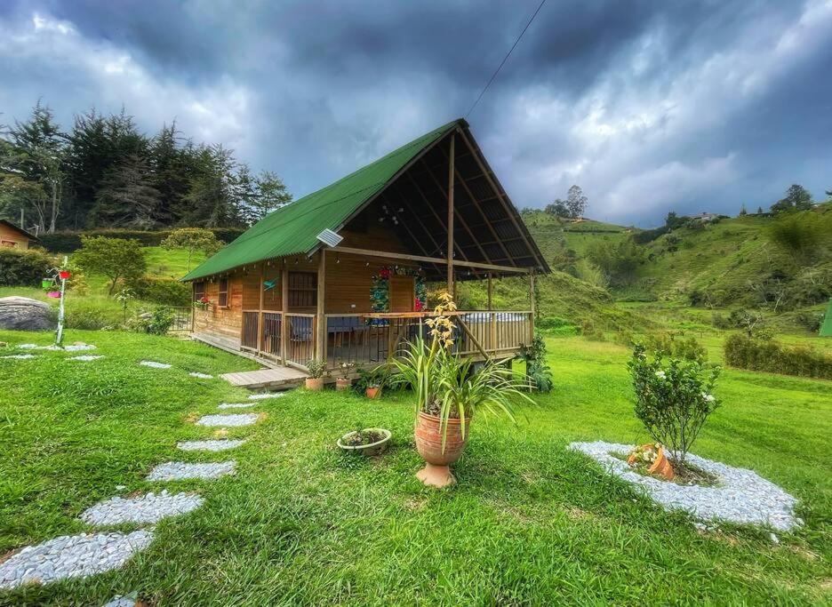 uma casa com um telhado verde num campo de relva em Espectacular Cabaña Loft en Guatape - Jacuzzi em El Peñol