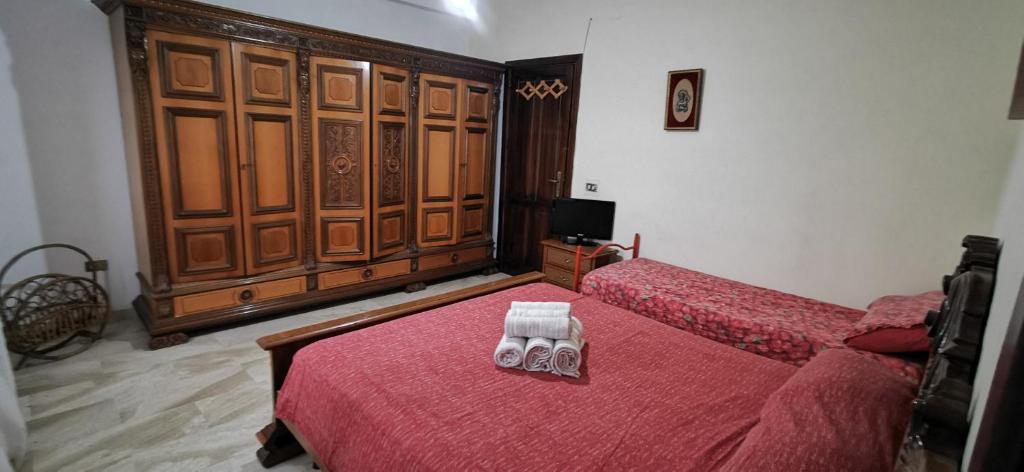 um quarto com 2 camas com lençóis vermelhos e uma televisão em B&B Calù em Cittadella del Capo