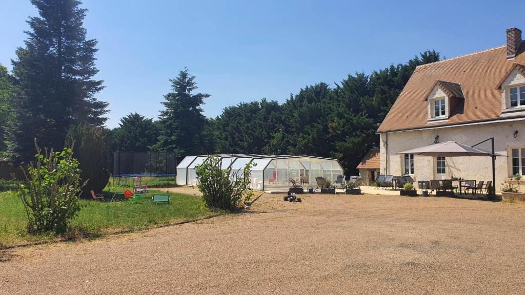 a greenhouse in a yard next to a house at Bois de Crâne in Landes-le-Gaulois