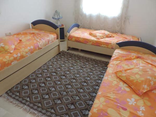 1 dormitorio con 2 camas y alfombra en Appartement de charme en Nabeul