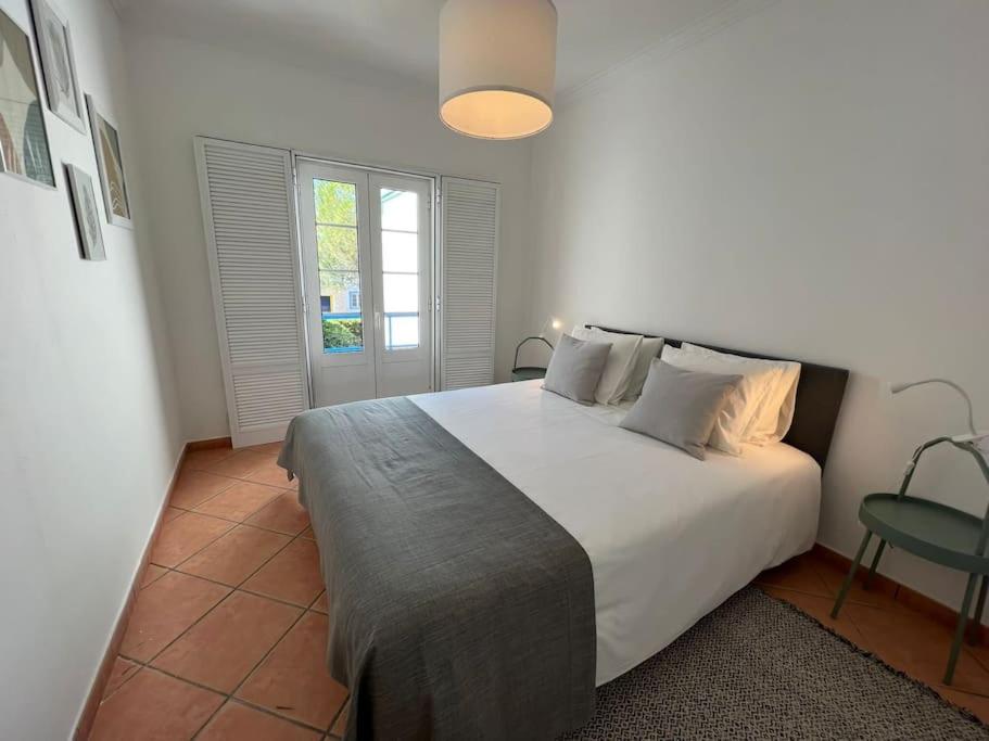Un dormitorio con una gran cama blanca y una ventana en Moradia V3 na Praia Verde en Castro Marim