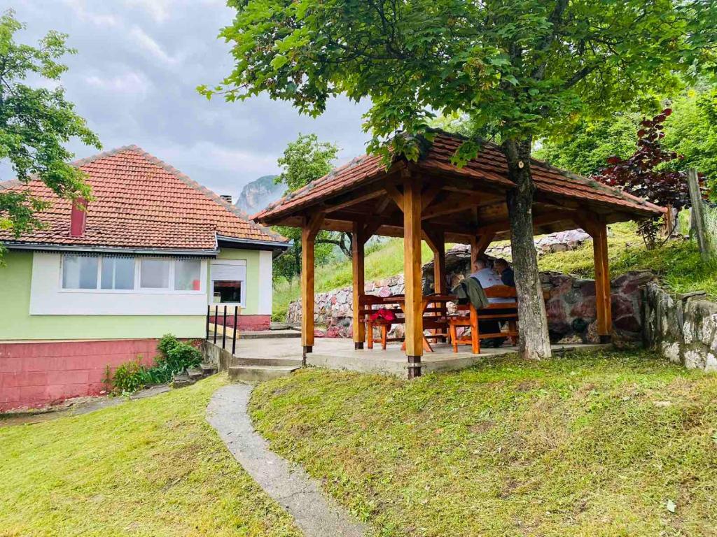 un cenador de madera en un patio con una casa en Seosko Domaćinstvo Vulević, en Andrijevica