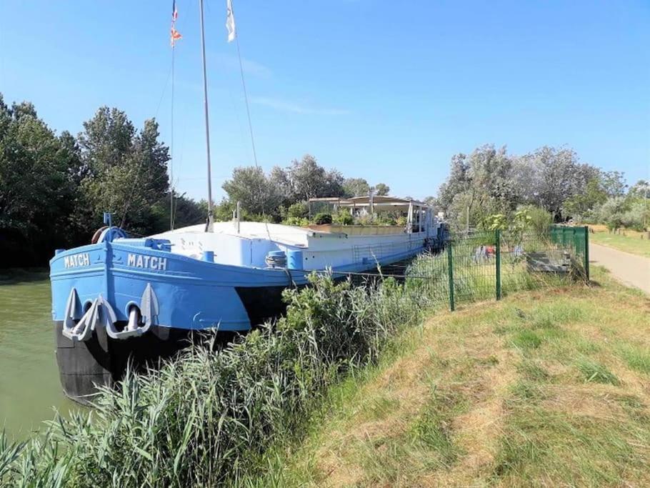 un bateau bleu garé sur le bord d'une rivière dans l'établissement Péniche Match, à Arles