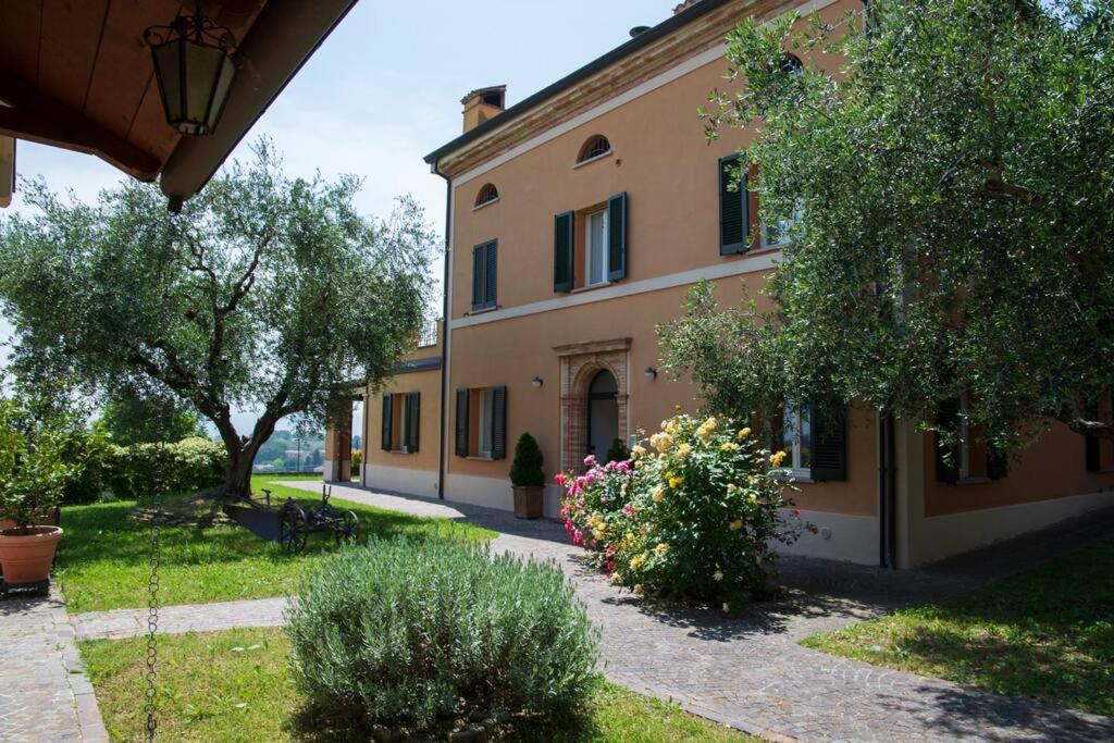 Villa Fiore nel Borgo d'Arte Novilara by Yohome في Novilara: مبنى كبير أمامه نباتات