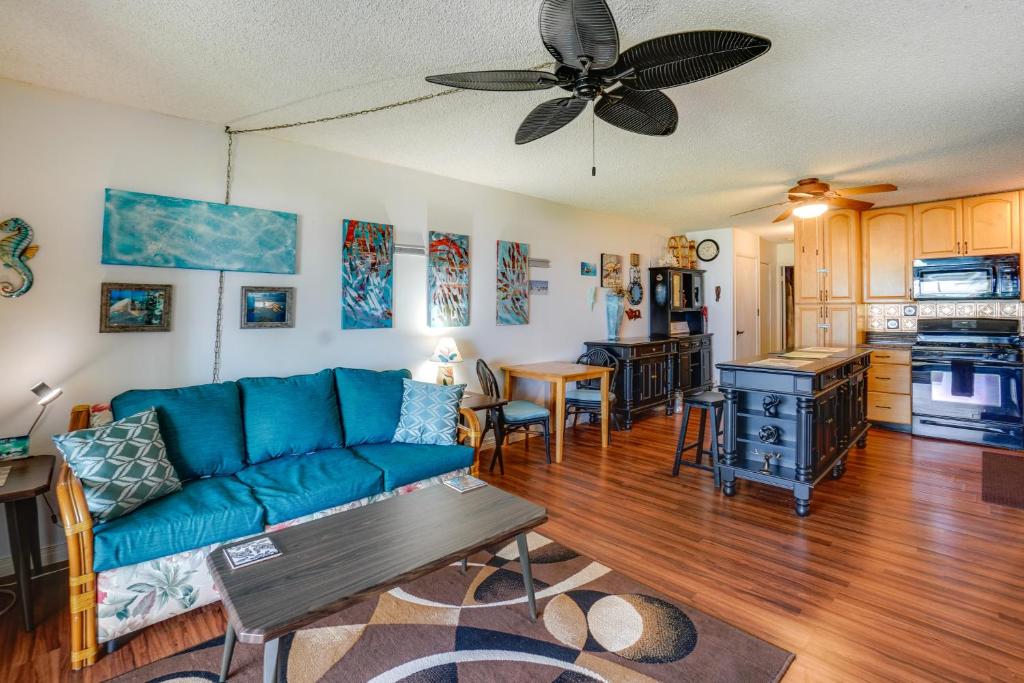 a living room with a blue couch and a kitchen at Molokai Island Retreat with Ocean View and Pool! in Kaunakakai