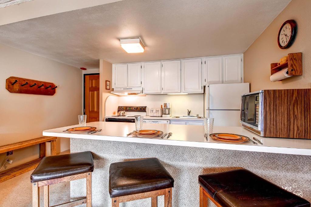 a kitchen with white cabinets and a counter with stools at Ideal Breck Location, Downtown, Mountain Views, Wi-Fi, Garage Parking TE405 in Breckenridge