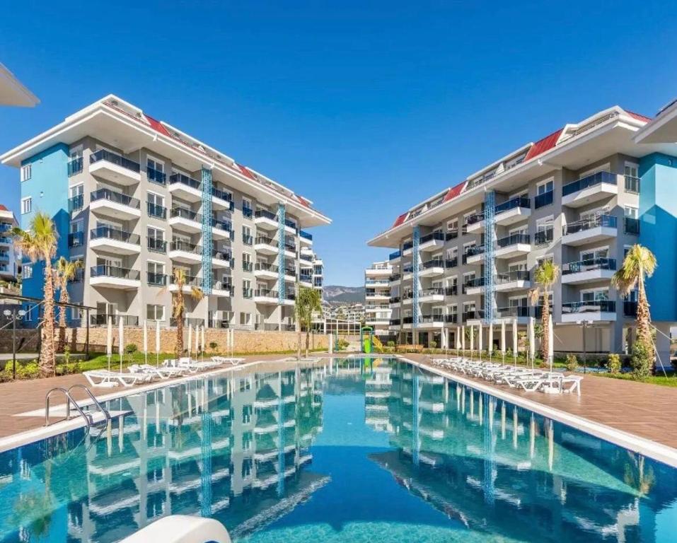 a swimming pool in front of two apartment buildings at Calypso Residence Kestel in Alanya