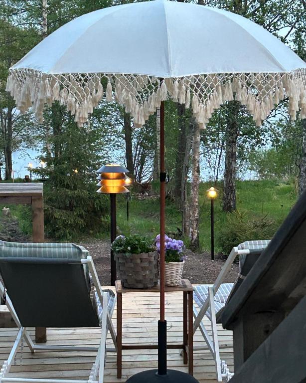 an umbrella on a deck with two chairs and a lamp at Sauna cabin in the heart of Nuuksio National Park - Mökki Nuuksiossa in Espoo