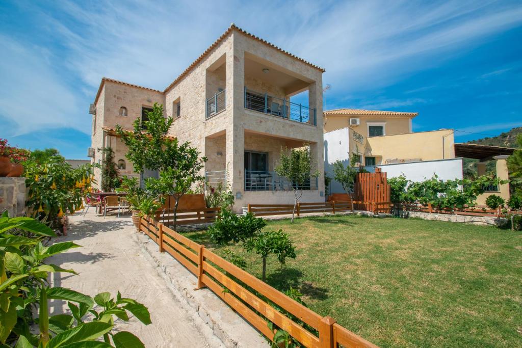 una casa grande con una valla y un patio en Liri's Apartments, en Kalamaki