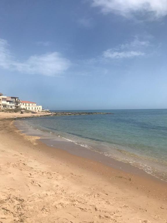 a sandy beach with the ocean and buildings in the background at Mamà Home-Casuzze in Villaggio Azzurro