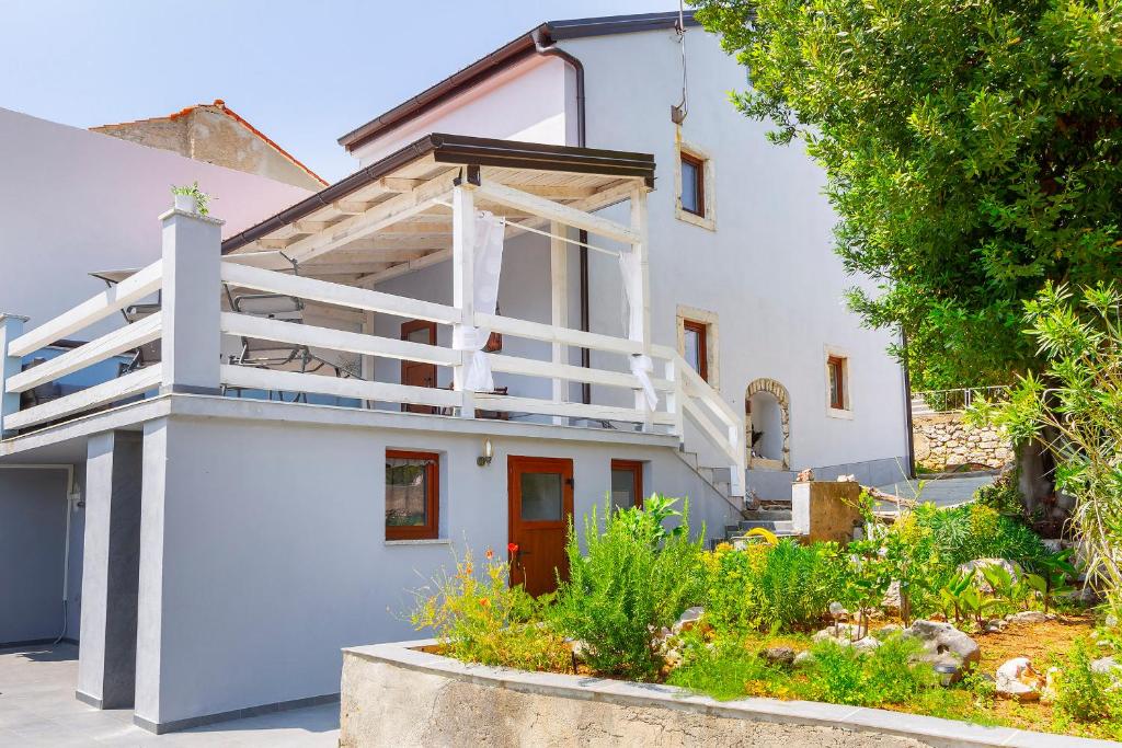 a white house with a staircase in a yard at Apartments Kleine Perle Am Meer in Šilo