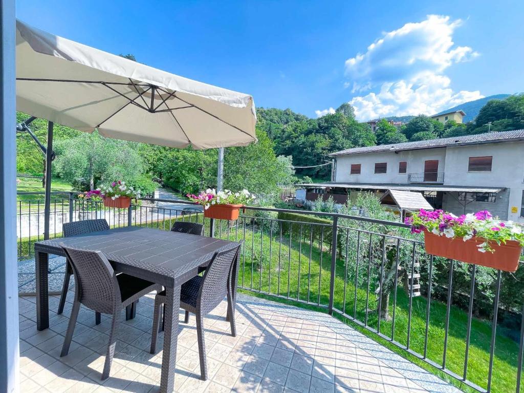 eine Terrasse mit einem Tisch, Stühlen und einem Sonnenschirm in der Unterkunft La Spiaggia Apartment in Bellagio