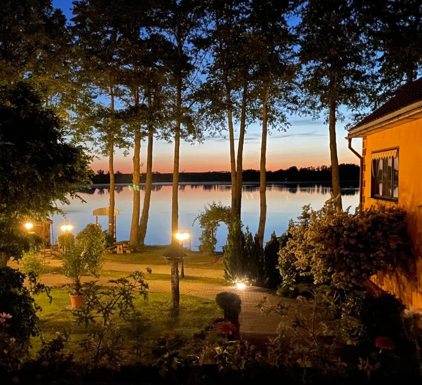Cette maison offre une vue sur un lac au crépuscule. dans l'établissement Seehof Netzen, à Kloster Lehnin