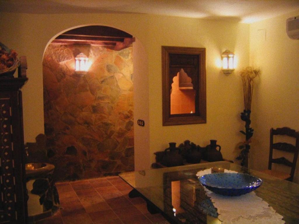 comedor con mesa de cristal y pared de piedra en Casa Rural Lares, en Casas de Don Pedro