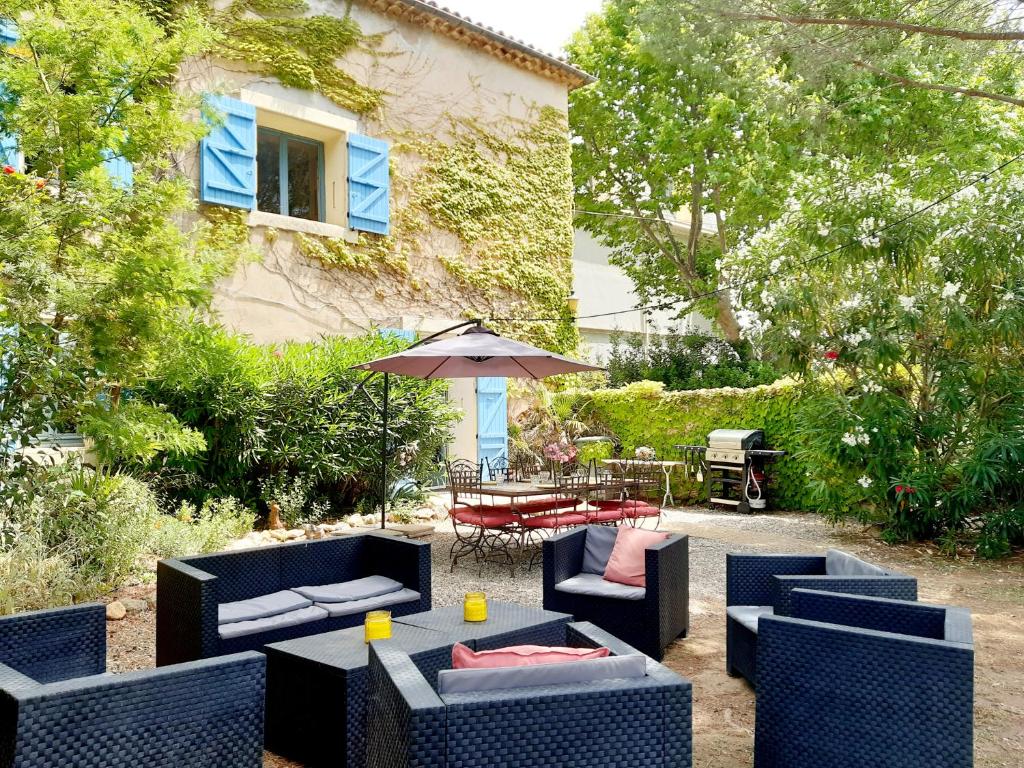 a patio with a table and chairs and an umbrella at Magnifiques maisons de campagne au sein d&#39;un vignoble in Cazouls-lès-Béziers