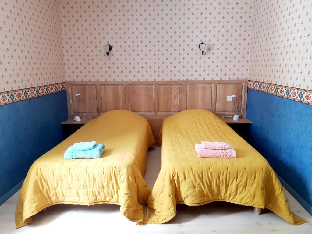 two beds in a room with yellow sheets and towels at Magnifiques maisons de campagne au sein d&#39;un vignoble in Cazouls-lès-Béziers