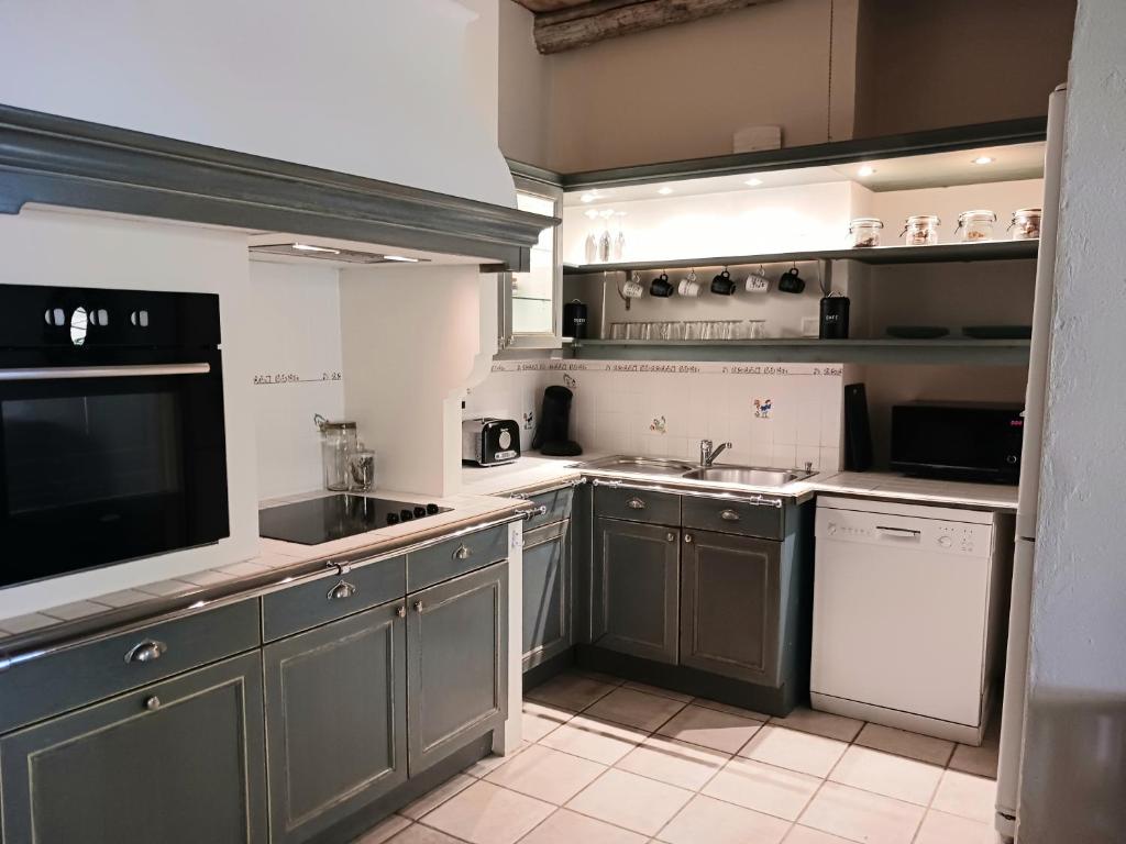 a large kitchen with gray cabinets and a sink at Magnifiques maisons de campagne au sein d&#39;un vignoble in Cazouls-lès-Béziers