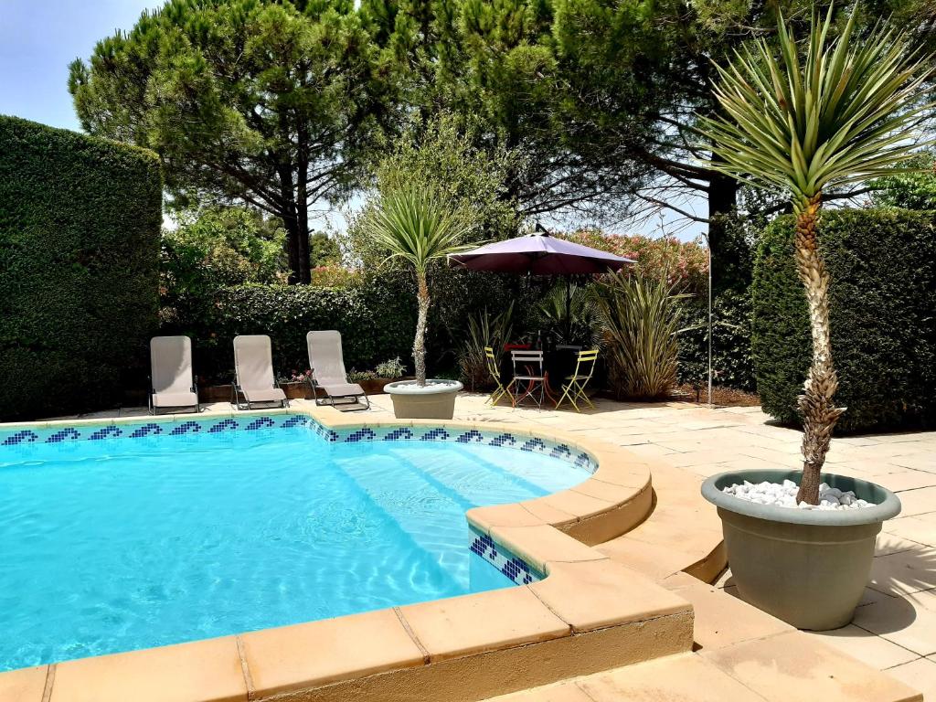 een zwembad met stoelen, een tafel en een parasol bij Magnifiques maisons de campagne au sein d'un vignoble in Cazouls-lès-Béziers