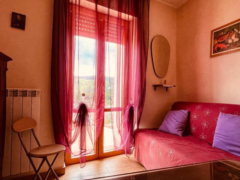 a living room with a red couch and a window at La Casa dei Panorami in Castelsaraceno