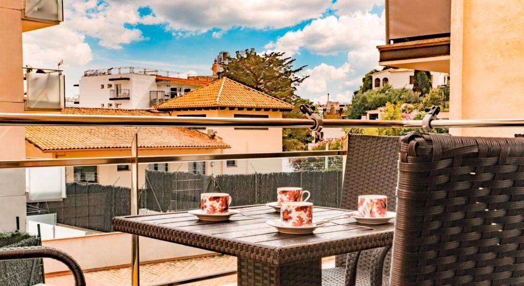 a table with cups and chairs on a balcony at Parrot’s House in Lloret de Mar