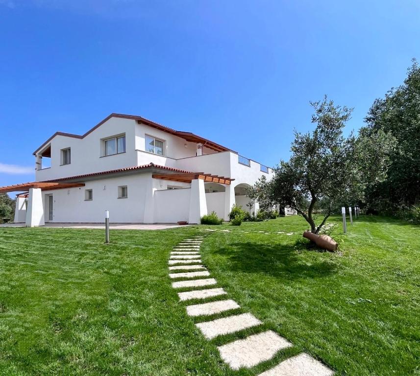 a house with a stone path in the grass at Sa Jacca Albergo Rurale in Siniscola