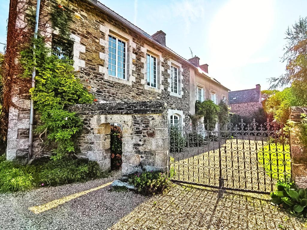 una vecchia casa in pietra con un cancello davanti di Ty Monde - Chambres d'hôtes en Finistère a Poullaouen