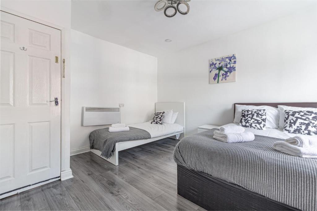 2Bedrooms, 4beds cosy family home, Free WiFi, Stay UK Homes في برمنغهام: سريرين في غرفة بجدران بيضاء وأرضية خشبية