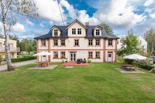 een groot huis met een tuin met banken en tafels bij Narcyz in Międzywodzie