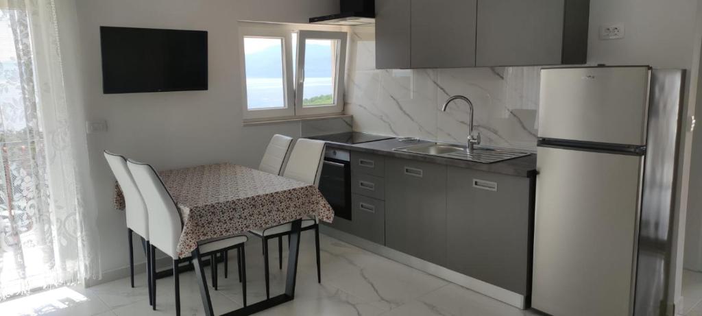 a kitchen with a refrigerator and a table and chairs at Apartments INBOX in Kostrena